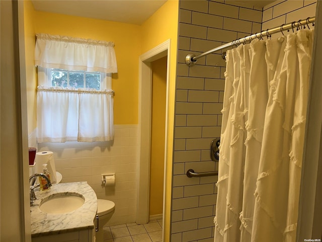 bathroom with curtained shower, tile patterned floors, toilet, vanity, and tile walls