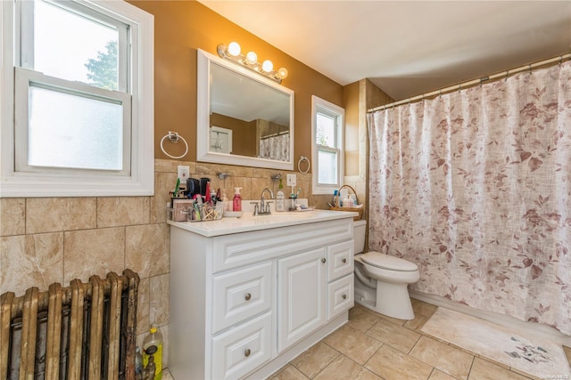 bathroom featuring radiator heating unit, vanity, tile walls, and toilet