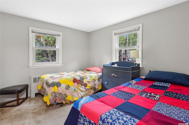 carpeted bedroom featuring multiple windows and radiator heating unit