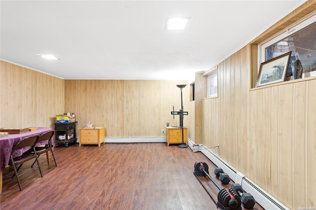 exercise room with dark wood-type flooring, wooden walls, and a baseboard heating unit