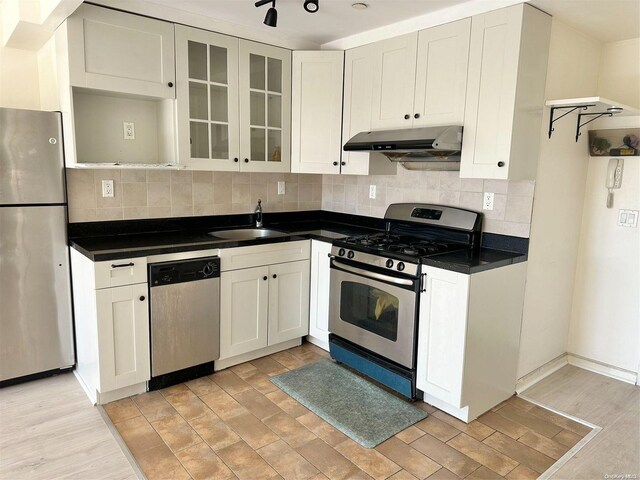 kitchen with decorative backsplash, appliances with stainless steel finishes, light wood-type flooring, sink, and white cabinets