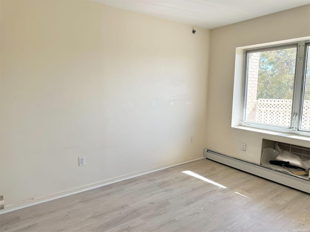 spare room featuring light wood-type flooring and baseboard heating