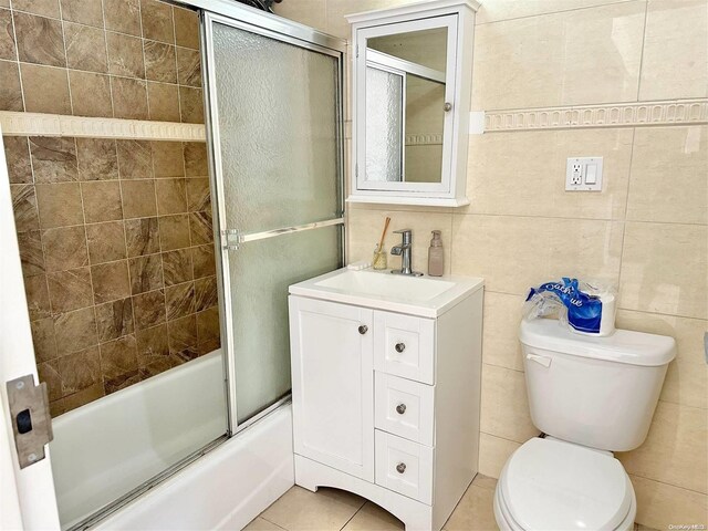 full bathroom featuring tile patterned flooring, enclosed tub / shower combo, toilet, vanity, and tile walls