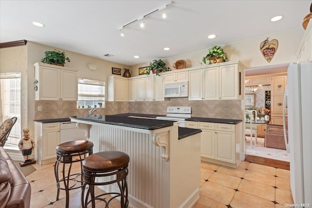 kitchen featuring a kitchen bar, backsplash, a center island, and white appliances