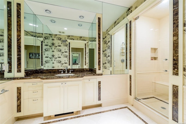 bathroom with tile patterned flooring, vanity, and walk in shower