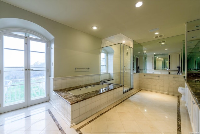 full bathroom featuring tile patterned flooring, separate shower and tub, toilet, and a healthy amount of sunlight