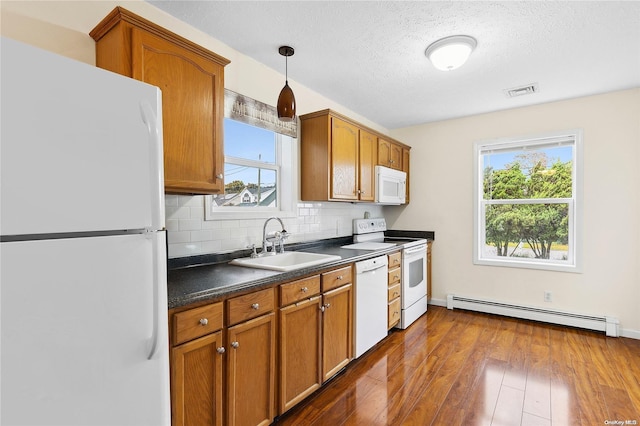 kitchen featuring white appliances, a baseboard heating unit, sink, hanging light fixtures, and dark hardwood / wood-style flooring