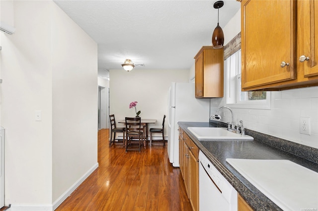 kitchen featuring pendant lighting, white dishwasher, sink, dark hardwood / wood-style floors, and decorative backsplash