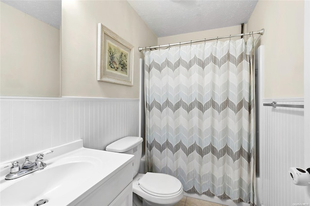 bathroom featuring tile patterned floors, vanity, a textured ceiling, toilet, and curtained shower