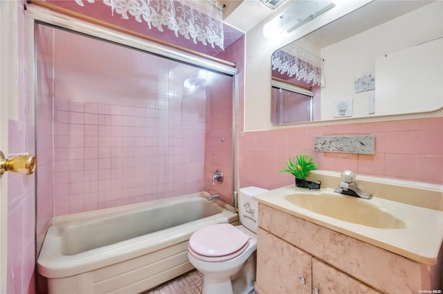 full bathroom featuring tiled shower / bath combo, tile patterned floors, toilet, vanity, and tile walls