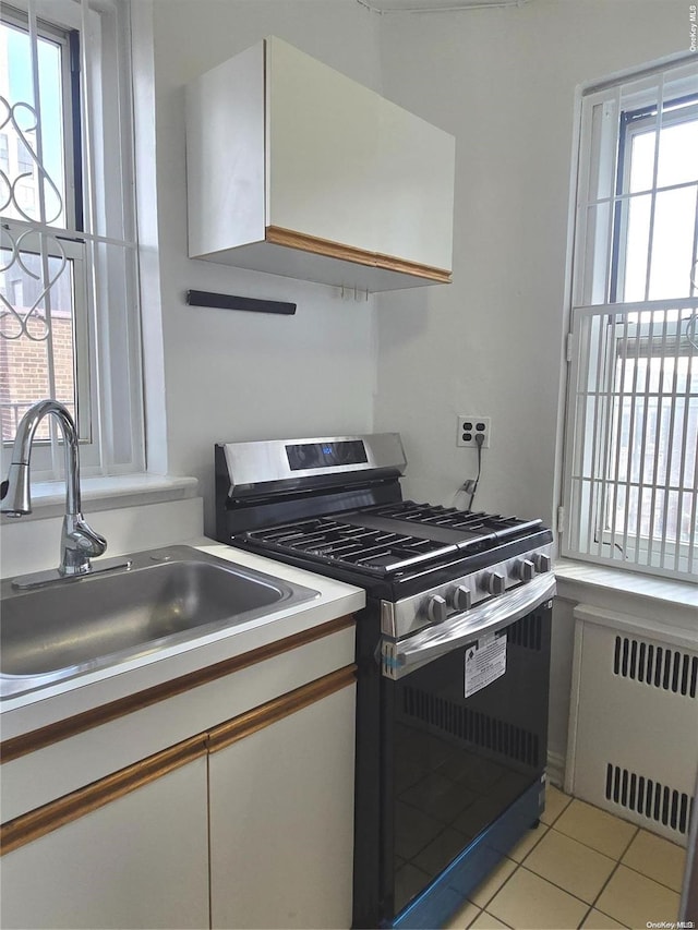 kitchen featuring black gas range, plenty of natural light, white cabinetry, and radiator