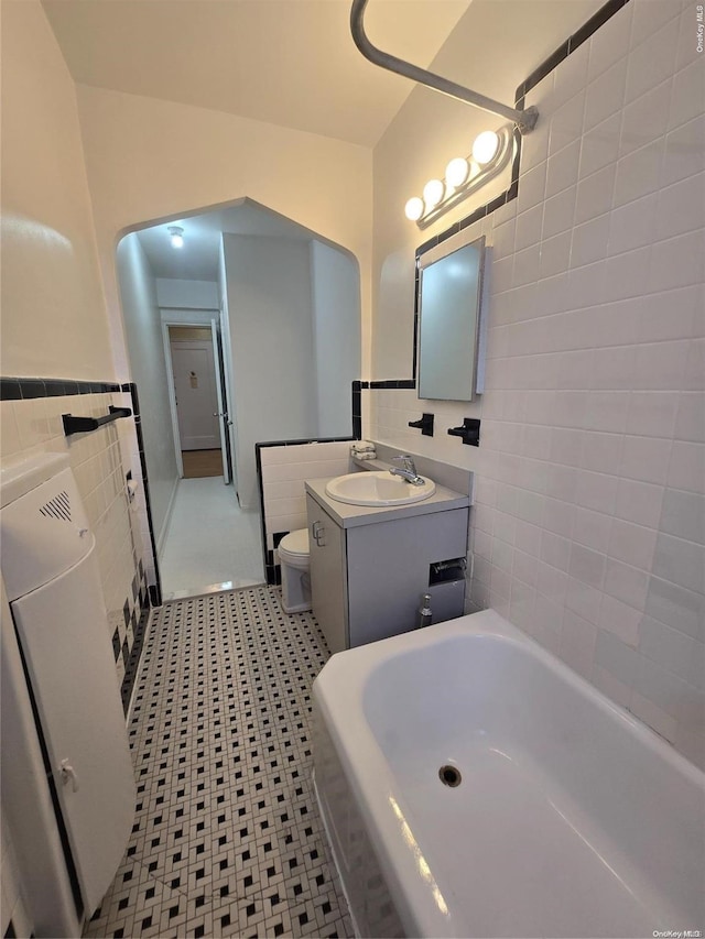 65-41 Booth St Unit 6K, Rego Park, NY 11374 - full bath with tile walls, toilet, a bath, vanity, and tile patterned flooring