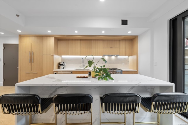 kitchen featuring light brown cabinets, backsplash, a center island, and sink