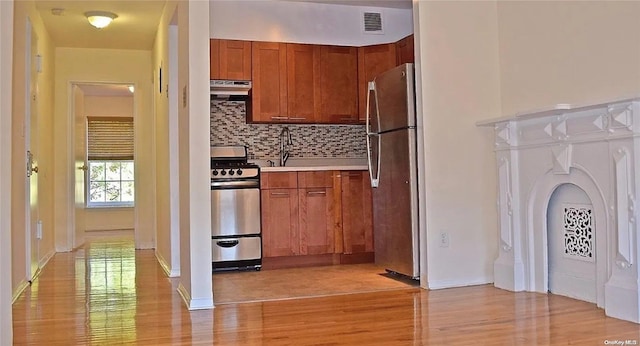 kitchen featuring tasteful backsplash, sink, stainless steel appliances, and light wood-type flooring