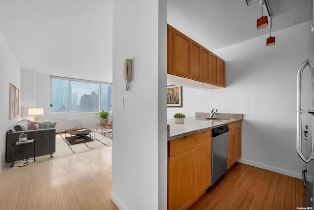 kitchen featuring dishwasher, light hardwood / wood-style floors, light stone countertops, and sink