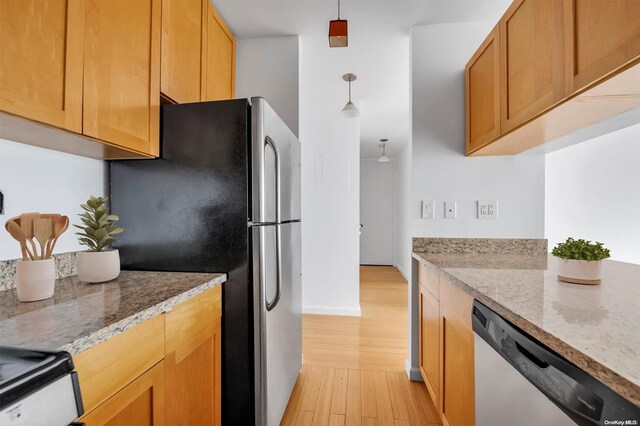 kitchen with pendant lighting, light hardwood / wood-style floors, light stone countertops, and appliances with stainless steel finishes