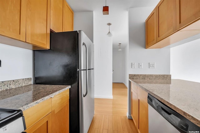 kitchen featuring appliances with stainless steel finishes, light hardwood / wood-style floors, light stone counters, and hanging light fixtures