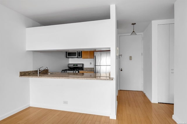 kitchen featuring hanging light fixtures, sink, light hardwood / wood-style floors, and appliances with stainless steel finishes