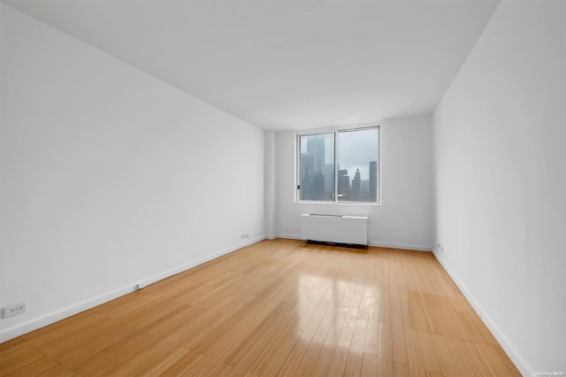 unfurnished room with light hardwood / wood-style floors and radiator