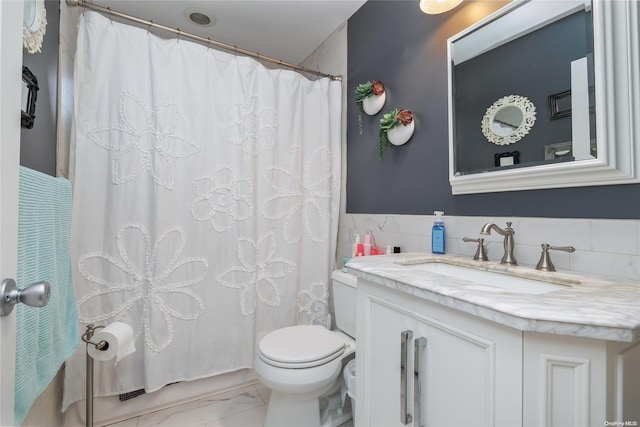 bathroom with vanity, toilet, and tile walls