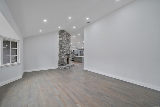 unfurnished living room featuring baseboards, recessed lighting, wood finished floors, and lofted ceiling