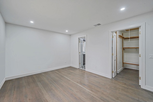 unfurnished bedroom with a spacious closet, recessed lighting, attic access, visible vents, and wood finished floors
