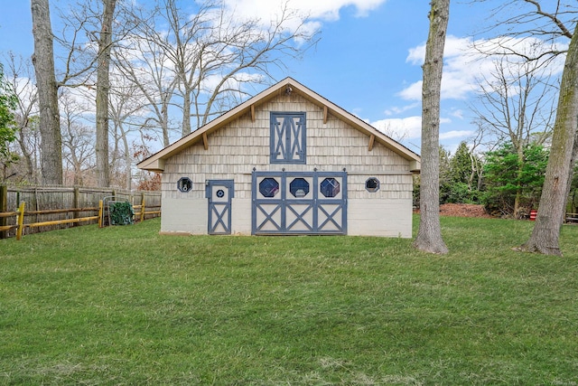 view of barn with fence and a lawn