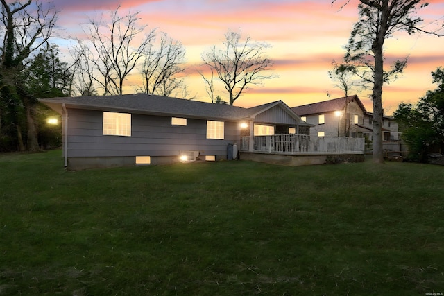 back of property at dusk with a yard, a deck, and board and batten siding