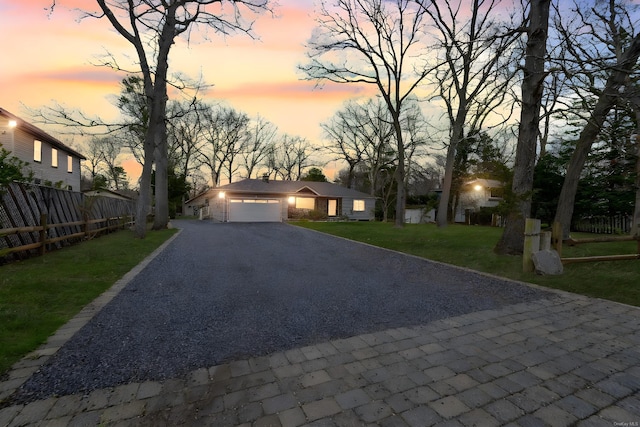 view of front of property featuring a yard, fence, a garage, and aphalt driveway