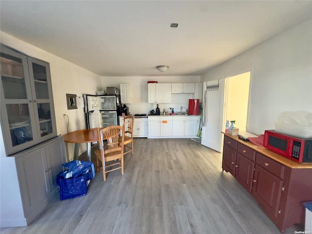 56 Woodcliff Trl, Baiting Hollow, NY 11933 - kitchen with light wood finished floors, white cabinets, a sink, and freestanding refrigerator