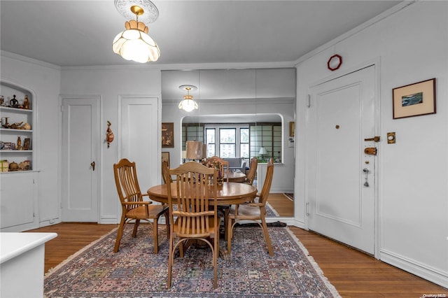 dining space featuring wood-type flooring and crown molding