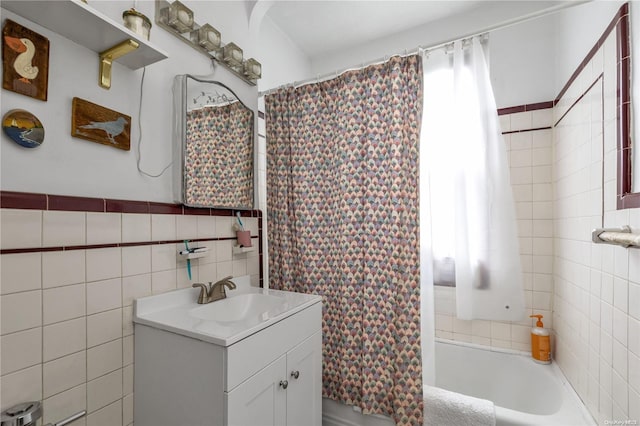 bathroom featuring vanity, shower / bathtub combination with curtain, and tile walls