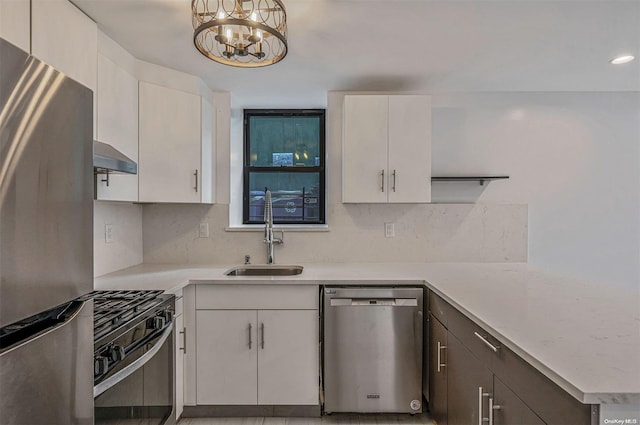 kitchen with appliances with stainless steel finishes, sink, white cabinets, a chandelier, and hanging light fixtures