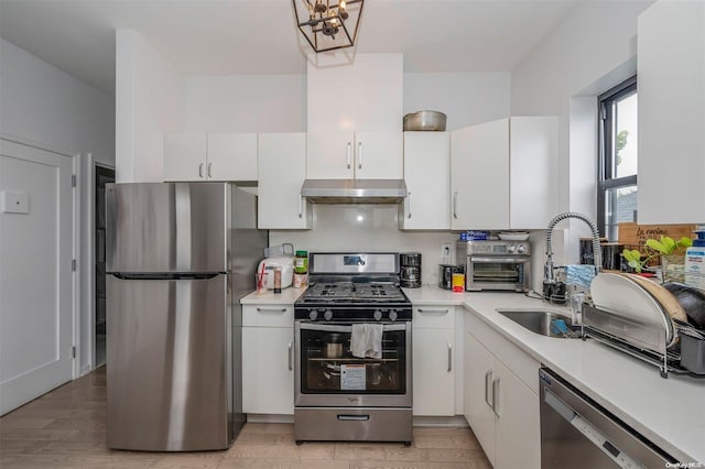 kitchen with sink, light wood-type flooring, range hood, white cabinetry, and stainless steel appliances