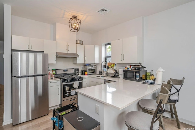 kitchen with white cabinetry, kitchen peninsula, a breakfast bar area, and appliances with stainless steel finishes