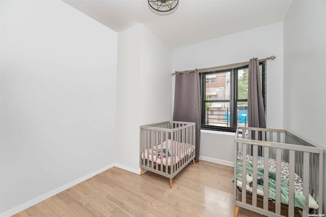 bedroom with light hardwood / wood-style flooring and a nursery area