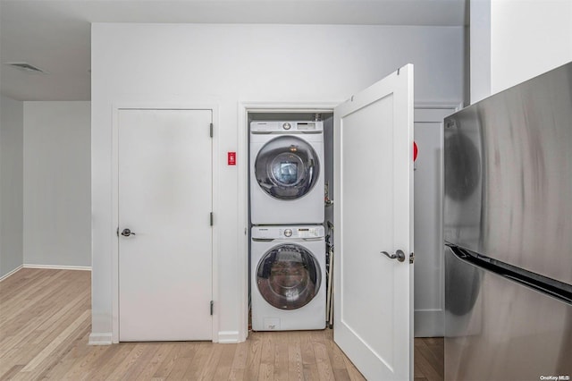 laundry room featuring stacked washer and dryer and light wood-type flooring