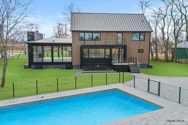 rear view of property featuring a lawn, a sunroom, a balcony, a fenced in pool, and a patio area