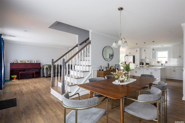 dining space featuring a chandelier, dark hardwood / wood-style floors, ornamental molding, and sink