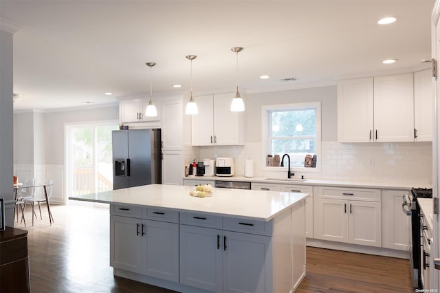 kitchen featuring appliances with stainless steel finishes, white cabinetry, hanging light fixtures, and sink