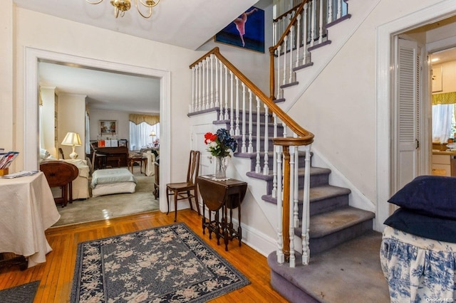 stairway with hardwood / wood-style floors and an inviting chandelier