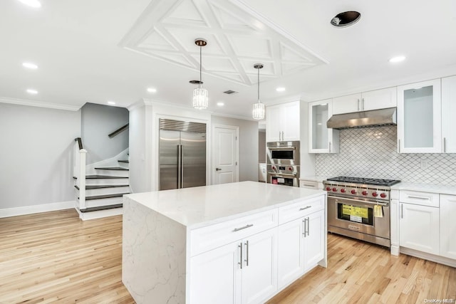 kitchen with white cabinets, premium appliances, a center island, and light hardwood / wood-style flooring