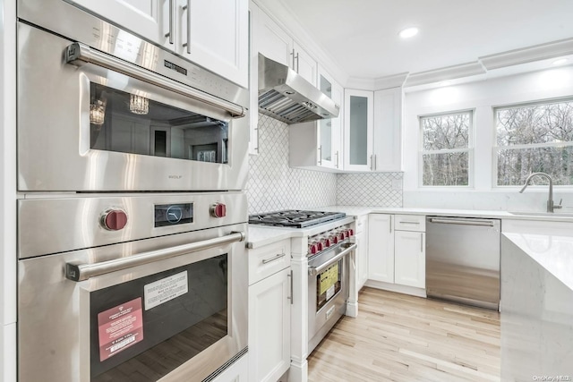 kitchen with white cabinetry, sink, decorative backsplash, appliances with stainless steel finishes, and light wood-type flooring