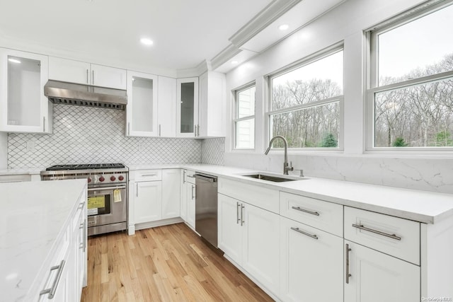 kitchen featuring appliances with stainless steel finishes, a wealth of natural light, white cabinets, and range hood