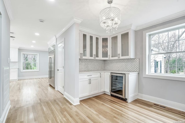 kitchen with built in fridge, hanging light fixtures, light hardwood / wood-style floors, white cabinetry, and beverage cooler