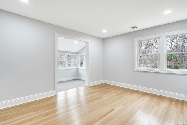 spare room with light hardwood / wood-style floors, vaulted ceiling, and a wealth of natural light