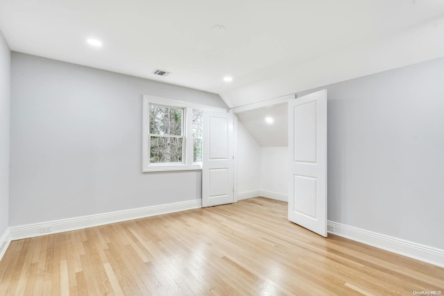 additional living space with light hardwood / wood-style flooring and vaulted ceiling