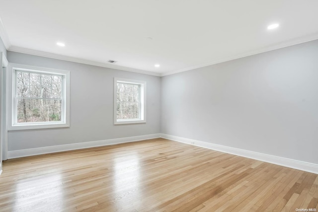 spare room featuring crown molding and light wood-type flooring