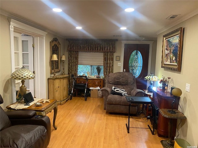 living area with crown molding and light hardwood / wood-style flooring