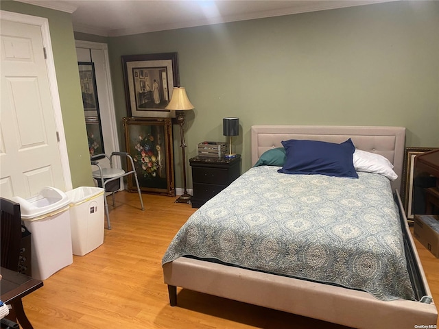 bedroom featuring light hardwood / wood-style floors, a closet, and crown molding